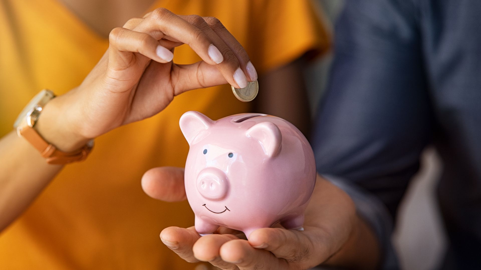 Person putting coin into a piggy bank